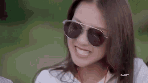 a woman wearing sunglasses and ear buds is smiling .