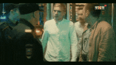 a man in a white shirt is being questioned by a police officer with a badge that says tht on it