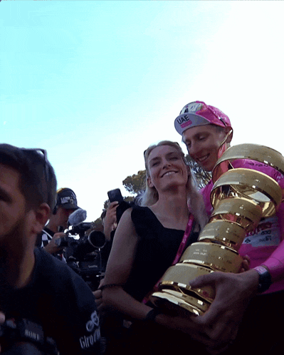 a man holding a trophy next to a woman wearing a pink uae hat