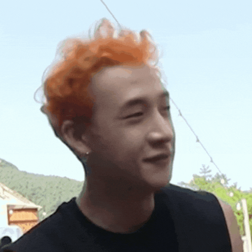 a man with red hair is wearing a black shirt and earrings and making a funny face .
