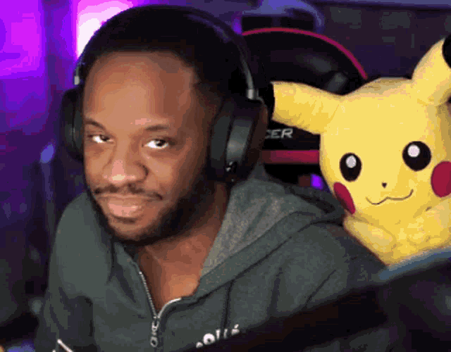 a man wearing headphones holds a stuffed pikachu on his lap