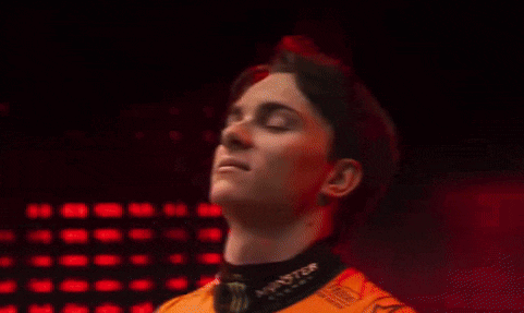 a young man wearing a monster energy shirt is looking at the camera in front of a red background .