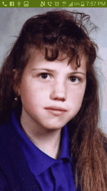 a young girl 's face is displayed on a cell phone screen at 7:57 pm
