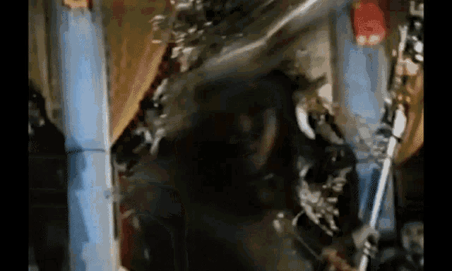 a close up of a person holding a sword in a room in a movie .