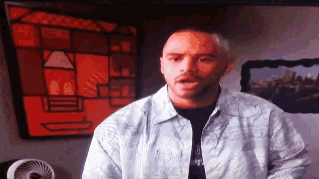 a man with a beard is standing in front of a painting