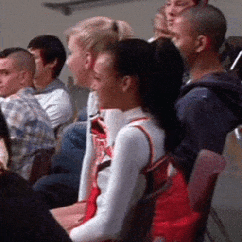 a group of people are sitting in a stadium and one of them is wearing a red and white outfit