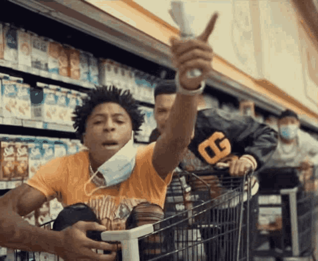 a man wearing a mask is pushing a shopping cart in a grocery store