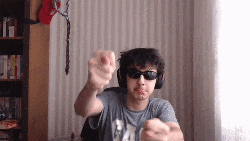 a man wearing sunglasses and headphones is pointing his finger