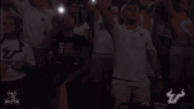 a crowd of people with their hands in the air and a bullpen logo in the background