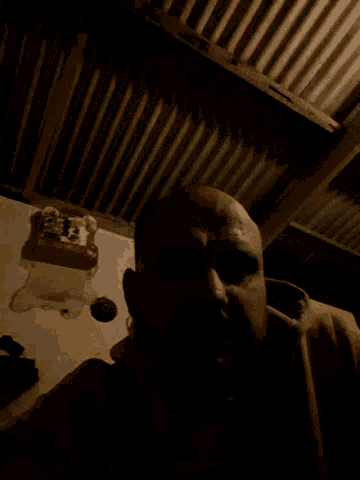 a man is sitting in a dark room with a phone on the wall