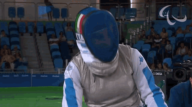 a man wearing a fencing mask is standing in front of a camera that says omega