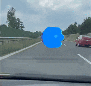 a red car is driving down a highway with a blue object in the windshield