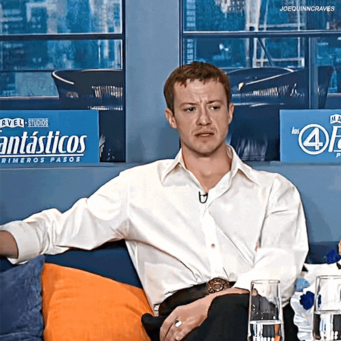 a man sits on a couch in front of a fantasticos sign