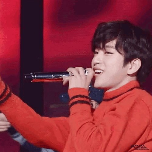 a young man in a red sweater is holding a microphone in his hand .