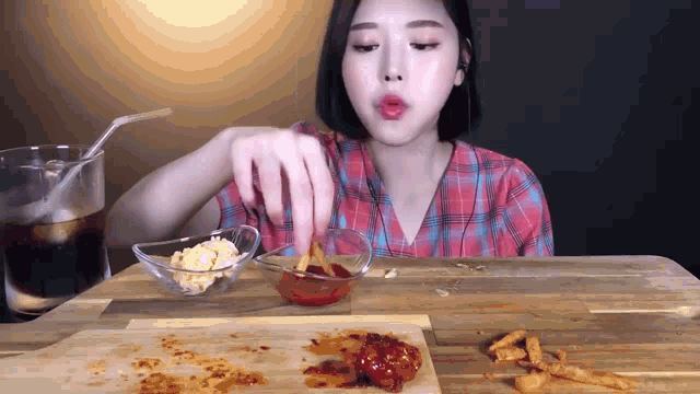 a woman in a plaid shirt is eating a meal