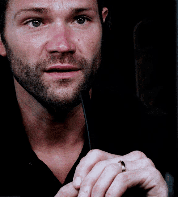 a man with a ring on his finger is looking at the camera