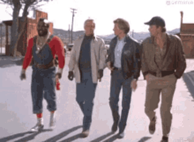 a group of four men are walking down a street .