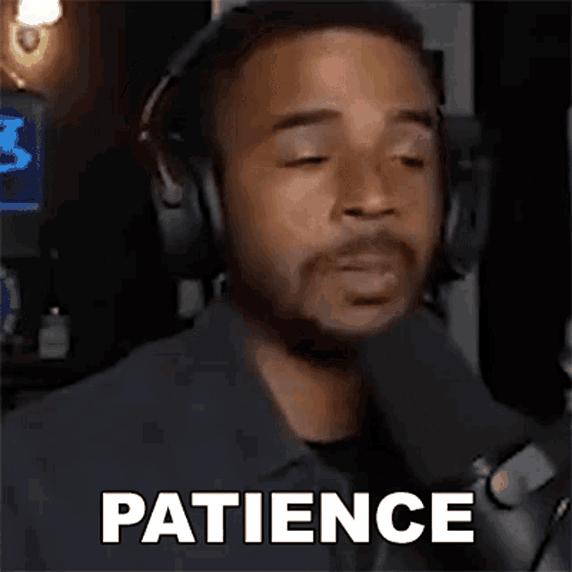 a man wearing headphones is talking into a microphone and the word patience is written on the screen .