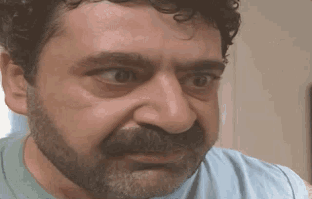 a man with a beard and curly hair is looking at the camera