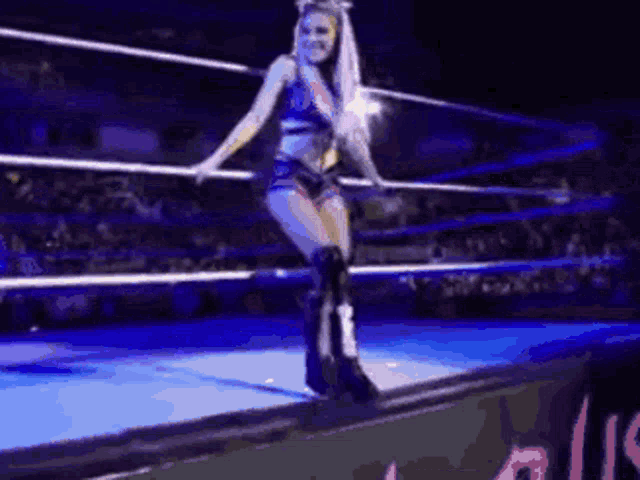 a woman is standing in a wrestling ring with her legs crossed .