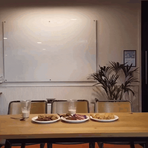 three plates of food are on a table in front of a whiteboard