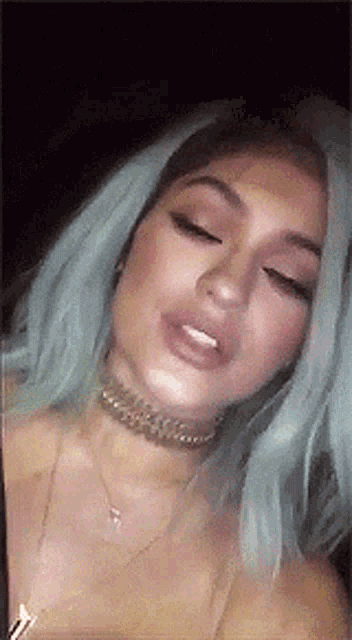 a close up of a woman with blue hair wearing a choker .