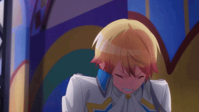 a boy with blonde hair and red hair is crying in front of a colorful wall