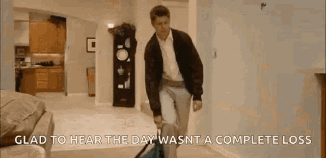 a man is walking down a hallway with a vacuum cleaner in his hand .