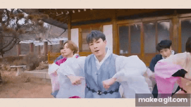 a group of young men are dancing in front of a building in a video .