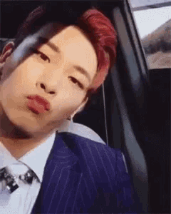 a man in a suit and tie is sitting in the back seat of a car with his mouth open .