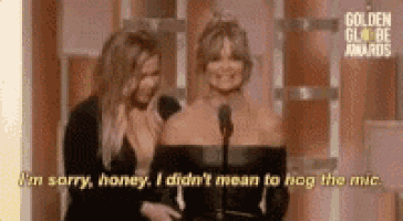 two women are standing next to each other in front of a microphone at a golden globes awards show .