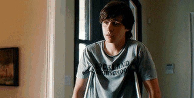 a young man with crutches and a shirt that says rock and roll school