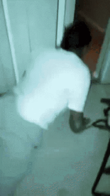 a person in a white shirt is bending over in a hallway