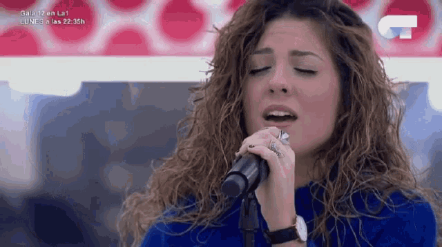 a woman singing into a microphone with a u on the bottom right