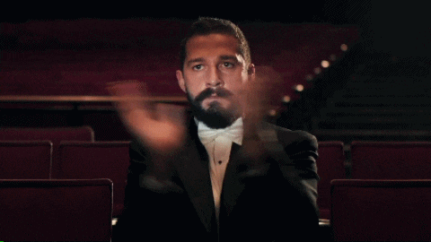 a man with a beard wearing a tuxedo and bow tie applauds