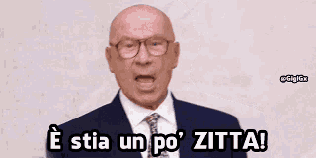 a bald man wearing glasses and a suit and tie says e stia un po zitta