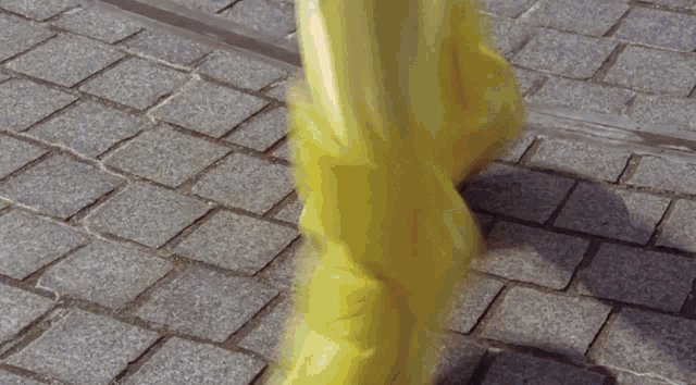 a person wearing a pair of yellow boots walking on a brick sidewalk
