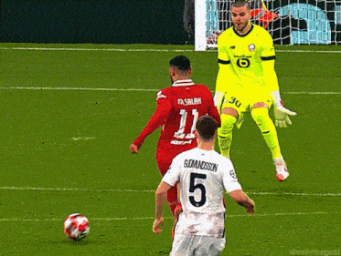 a soccer player with the number 5 on his back is about to kick the ball