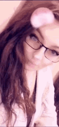 a woman wearing glasses is taking a selfie with a pink bubble on her nose .
