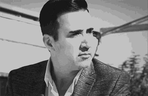 a man in a suit and white shirt is looking at the camera