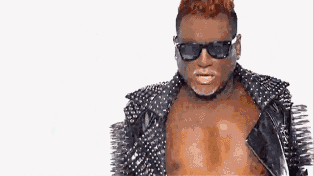 a man with red hair is wearing a black leather jacket with spikes on it .