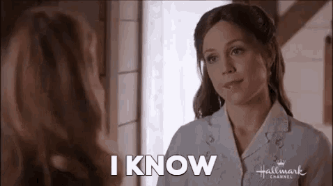 a woman is talking to another woman in front of a window and says `` i know '' .