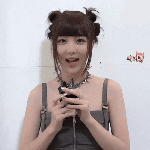 a woman wearing a necklace with spikes on it holds a cell phone