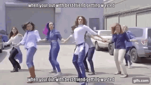a group of women are dancing in a parking lot in front of cars .