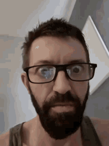 a man with glasses and a beard is looking down
