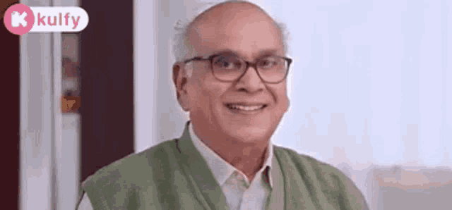 a man wearing glasses and a green vest is smiling .