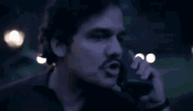 a man is talking on a cell phone in the dark .