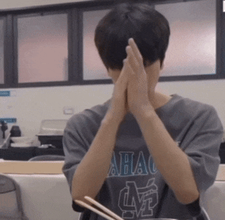a man wearing a shirt that says abac is covering his face with his hands