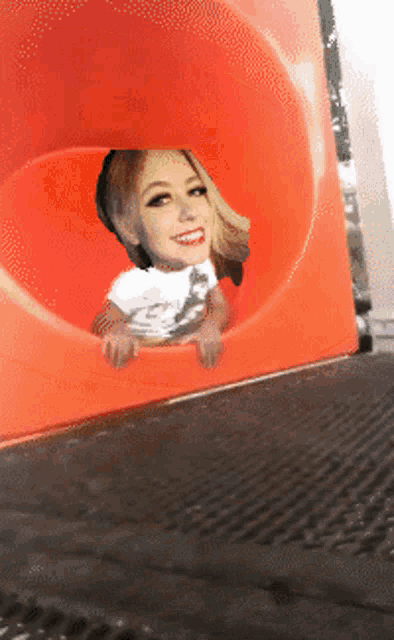 a woman in a white shirt is looking out of a red tube