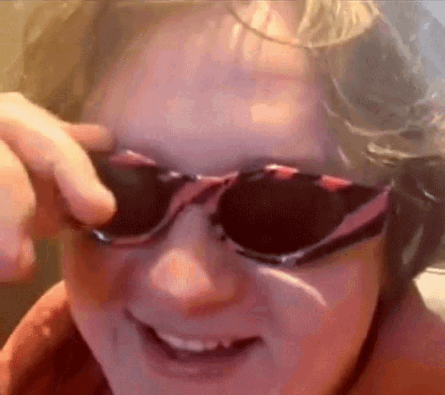 a close up of a person wearing sunglasses and smiling .